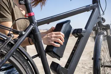 Persoon plaatst lithium-ion batterij in elektrische fiets – e-bike accu opladen